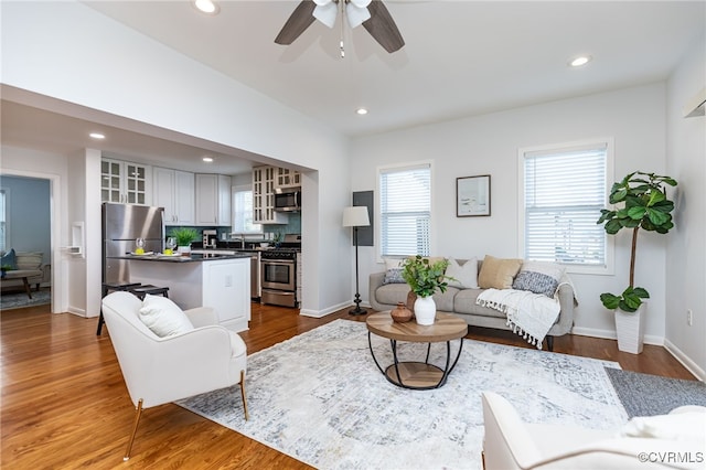 living room featuring ceiling fan, wood-type flooring, and sink