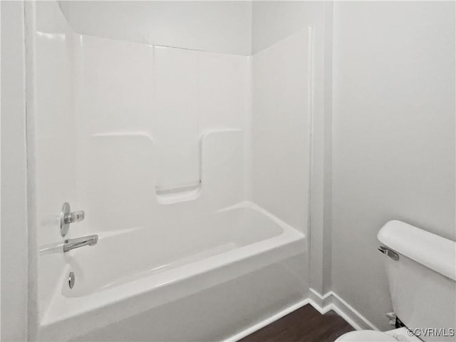 bathroom featuring wood-type flooring, washtub / shower combination, and toilet