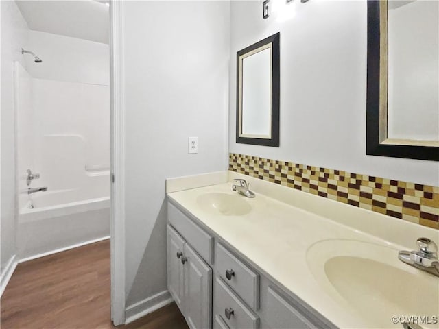 bathroom with wood-type flooring, shower / bathing tub combination, vanity, and decorative backsplash