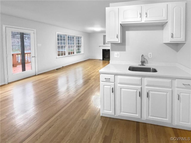 kitchen featuring plenty of natural light, sink, white cabinets, and light hardwood / wood-style flooring