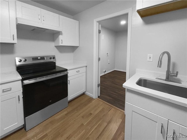 kitchen featuring sink, hardwood / wood-style floors, white cabinets, and stainless steel electric range