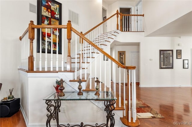 staircase featuring hardwood / wood-style floors and a high ceiling