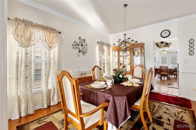 dining area with crown molding, hardwood / wood-style flooring, and a notable chandelier