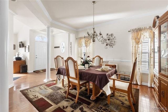 dining room with ornate columns, crown molding, hardwood / wood-style flooring, and a chandelier