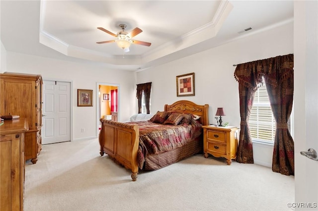 carpeted bedroom with ensuite bathroom, ceiling fan, ornamental molding, and a raised ceiling