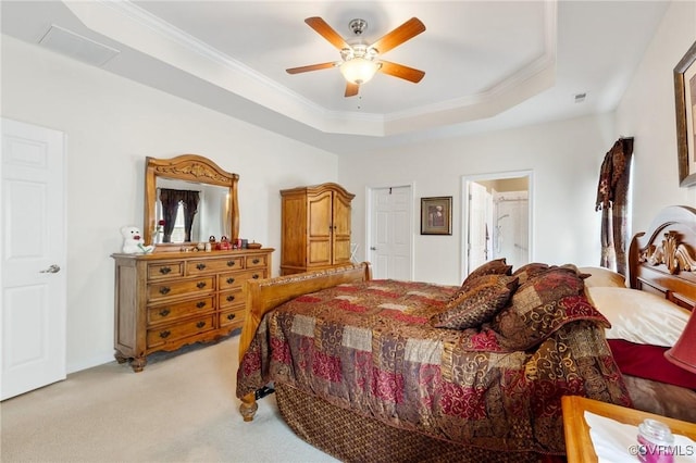 bedroom with ceiling fan, ensuite bathroom, ornamental molding, light colored carpet, and a raised ceiling