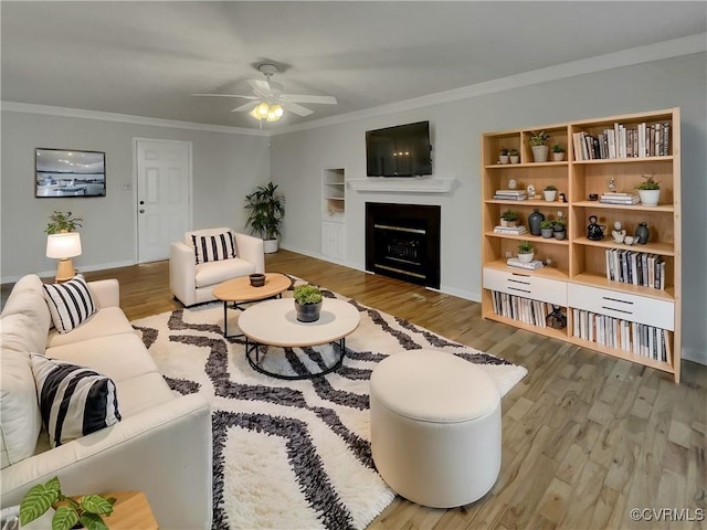 living room featuring crown molding, hardwood / wood-style floors, built in features, and ceiling fan