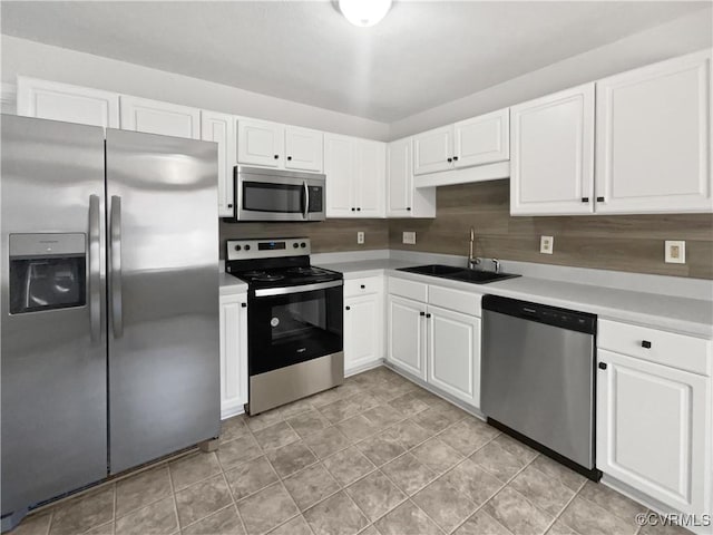 kitchen with sink, light tile patterned floors, white cabinets, and appliances with stainless steel finishes