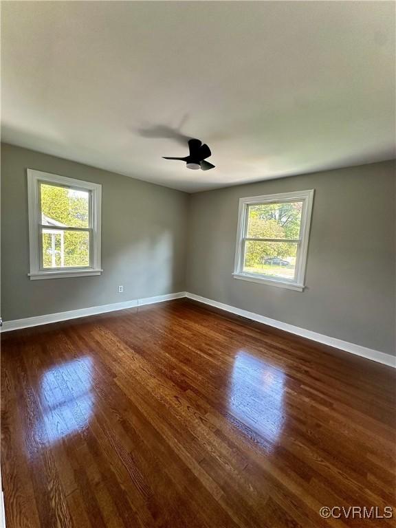 spare room featuring ceiling fan, dark hardwood / wood-style floors, and a healthy amount of sunlight