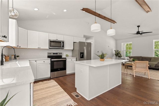 kitchen with sink, appliances with stainless steel finishes, a kitchen island, pendant lighting, and white cabinets