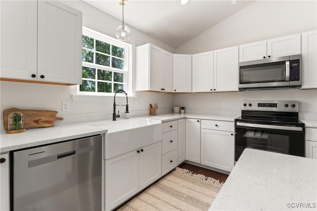 kitchen featuring appliances with stainless steel finishes, decorative light fixtures, white cabinetry, sink, and light stone counters