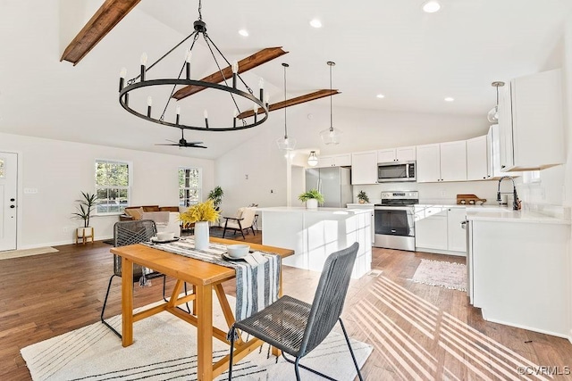 dining area featuring hardwood / wood-style flooring, ceiling fan, sink, and high vaulted ceiling