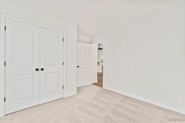 unfurnished bedroom with light colored carpet and a closet