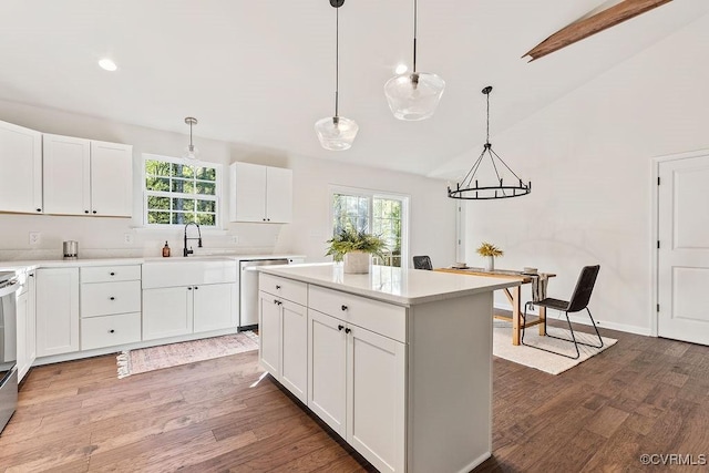 kitchen featuring lofted ceiling, a kitchen island, pendant lighting, stainless steel appliances, and white cabinets