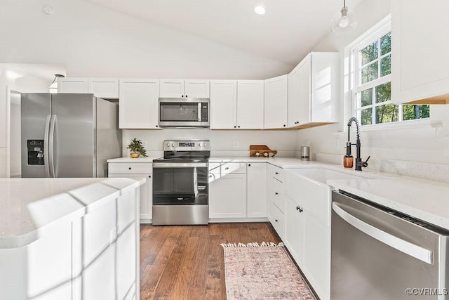 kitchen featuring white cabinetry, stainless steel appliances, dark hardwood / wood-style flooring, and vaulted ceiling