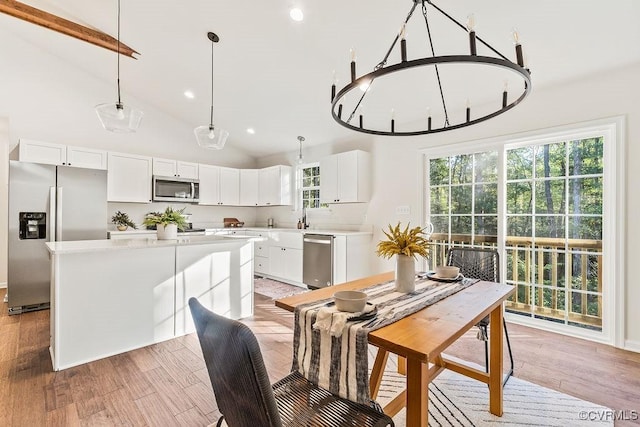 dining room with high vaulted ceiling, sink, and light hardwood / wood-style floors