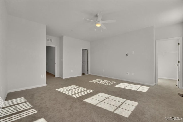 carpeted spare room with visible vents, baseboards, and ceiling fan