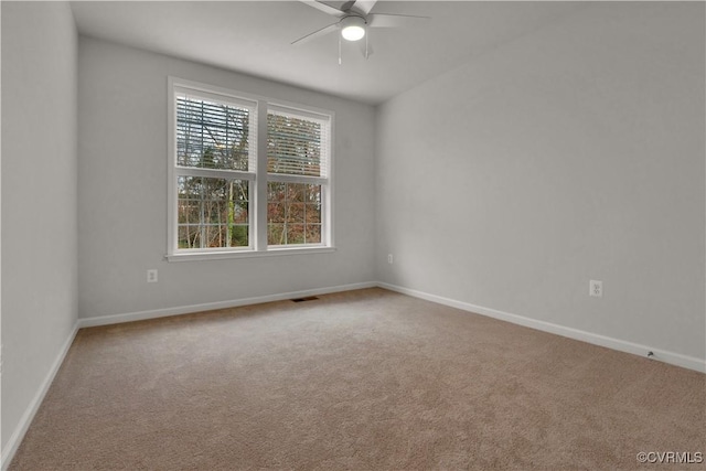 carpeted empty room with visible vents, baseboards, and ceiling fan