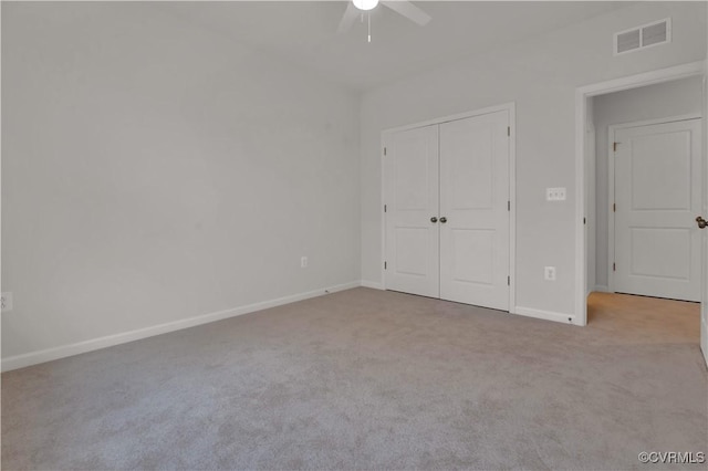 unfurnished bedroom featuring light colored carpet, ceiling fan, and a closet