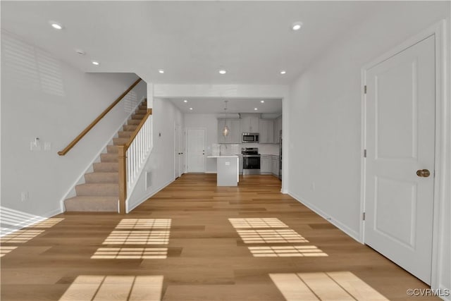 unfurnished living room featuring stairway, recessed lighting, and light wood-type flooring