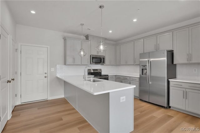 kitchen with pendant lighting, appliances with stainless steel finishes, gray cabinetry, light hardwood / wood-style floors, and kitchen peninsula