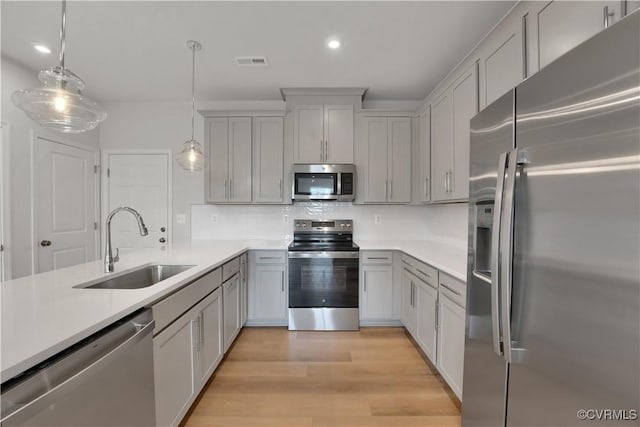 kitchen with stainless steel appliances, decorative light fixtures, gray cabinets, and sink