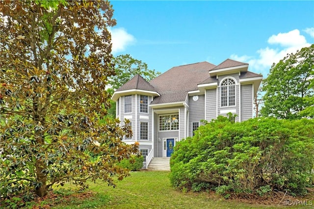 view of front of house featuring a front lawn and roof with shingles