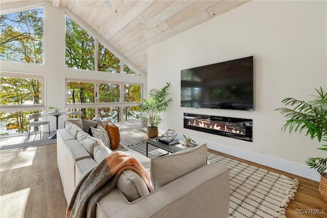 living room featuring high vaulted ceiling, wood finished floors, plenty of natural light, and a glass covered fireplace