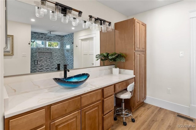 bathroom featuring wood finished floors, vanity, visible vents, baseboards, and a stall shower