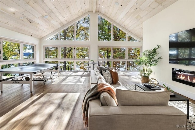 interior space with wooden ceiling, vaulted ceiling, and a glass covered fireplace