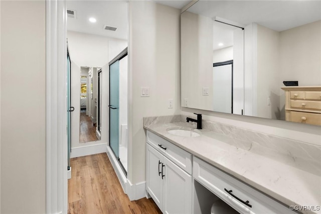 bathroom with recessed lighting, visible vents, a shower stall, vanity, and wood finished floors