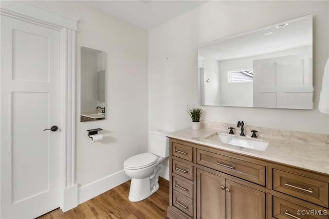 bathroom featuring baseboards, vanity, toilet, and wood finished floors