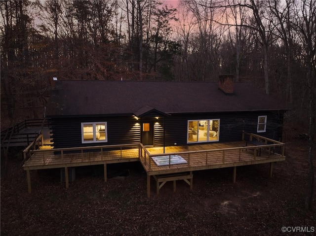 back house at dusk featuring a wooden deck