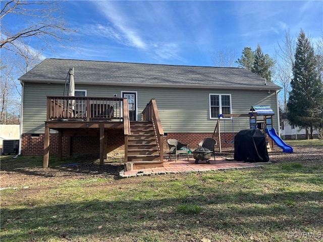 rear view of house with a fire pit, a yard, a patio, a wooden deck, and a playground