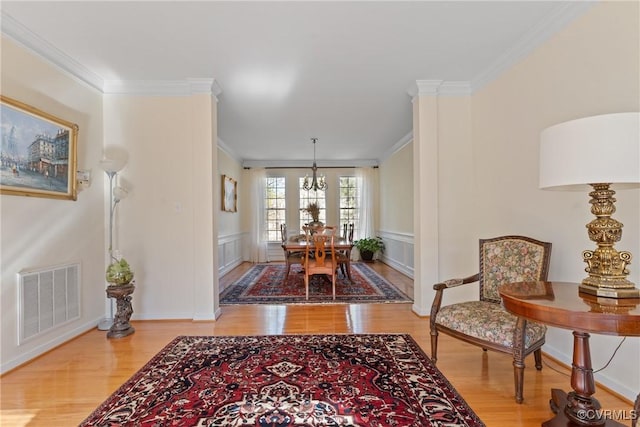 dining space featuring light wood-style floors, visible vents, and crown molding