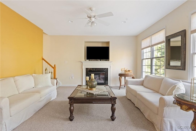 living room featuring light carpet, ceiling fan, baseboards, and a premium fireplace