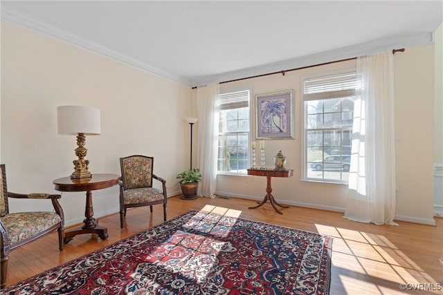 sitting room featuring light wood-style floors, crown molding, and baseboards