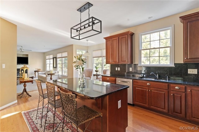 kitchen with a sink, tasteful backsplash, a breakfast bar, and stainless steel dishwasher