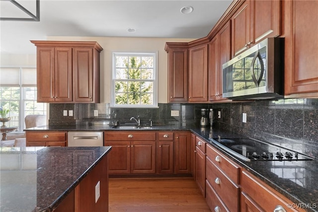 kitchen with dark stone counters, stainless steel appliances, a sink, and decorative backsplash