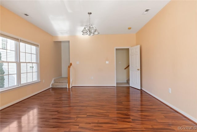 empty room featuring stairs, wood finished floors, and visible vents