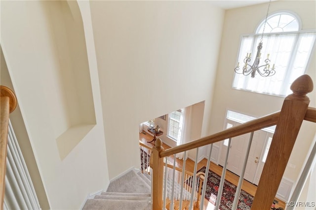 stairs featuring an inviting chandelier and a high ceiling