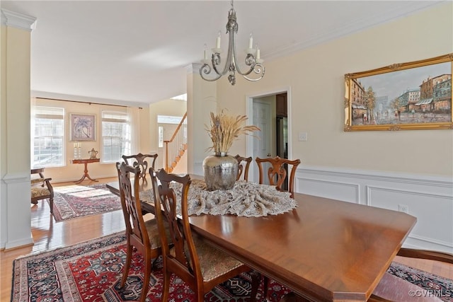 dining area with decorative columns, wood finished floors, stairs, crown molding, and a chandelier