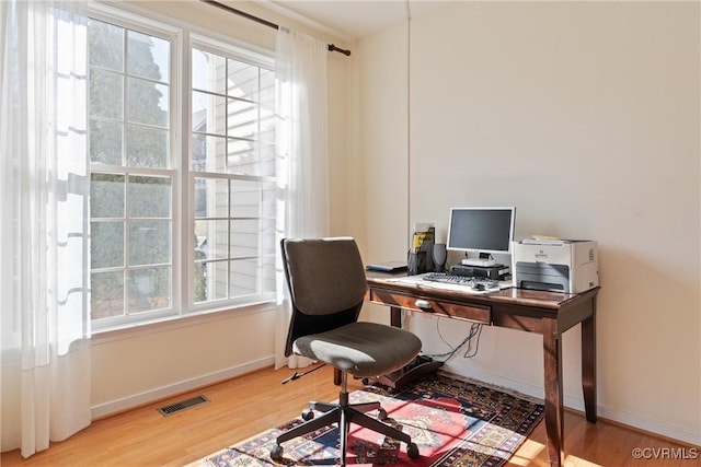 home office with a wealth of natural light, baseboards, and wood finished floors