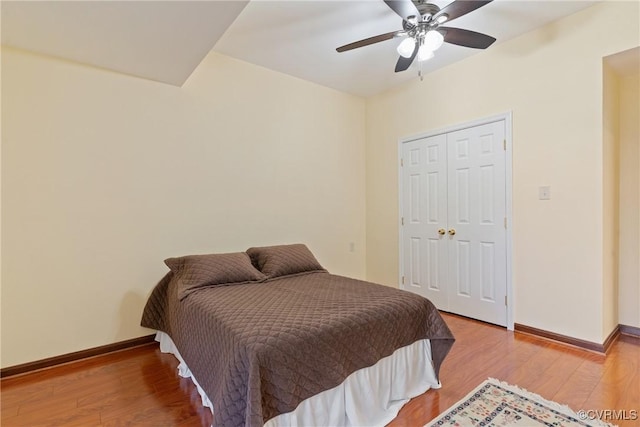 bedroom featuring a ceiling fan, a closet, baseboards, and wood finished floors