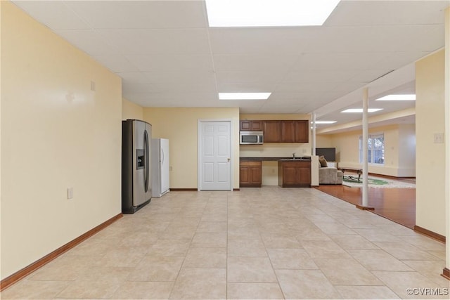 kitchen featuring a sink, baseboards, open floor plan, appliances with stainless steel finishes, and dark countertops