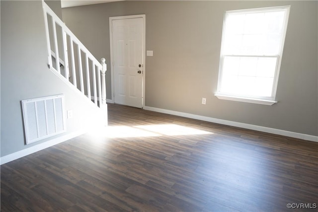 interior space featuring stairway, baseboards, visible vents, and dark wood-style flooring