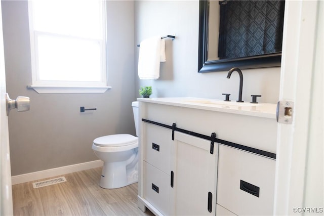 bathroom featuring toilet, wood finished floors, visible vents, vanity, and baseboards