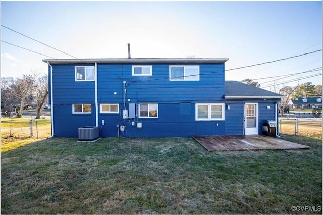 rear view of property featuring central AC and a lawn