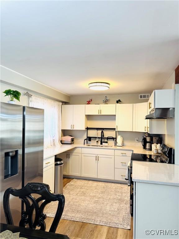 kitchen with sink, white cabinetry, stainless steel refrigerator with ice dispenser, range with electric stovetop, and light wood-type flooring