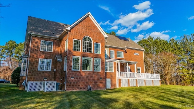 back of house featuring a lawn and solar panels